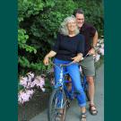 Kent Bradford and Barbara Zadra posing together on a bike in their garden.